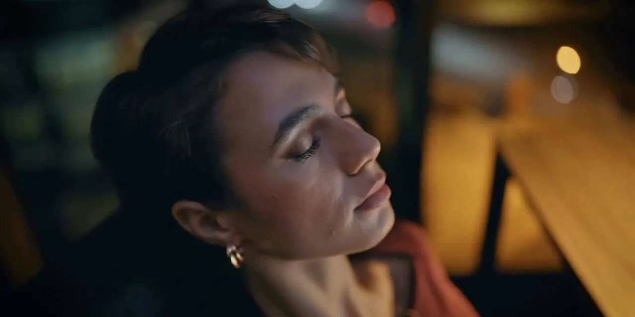 Mulher de olhos fechados sob luz noturna, frame do filme manifesto