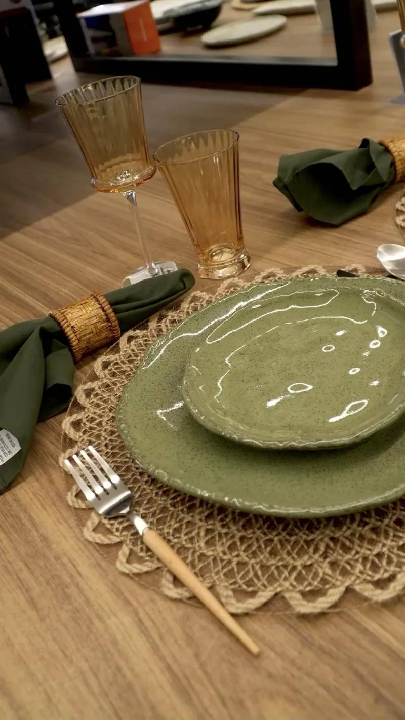 Mesa montada no desafio, com prato verde, taças âmbar e sousplat de fibra